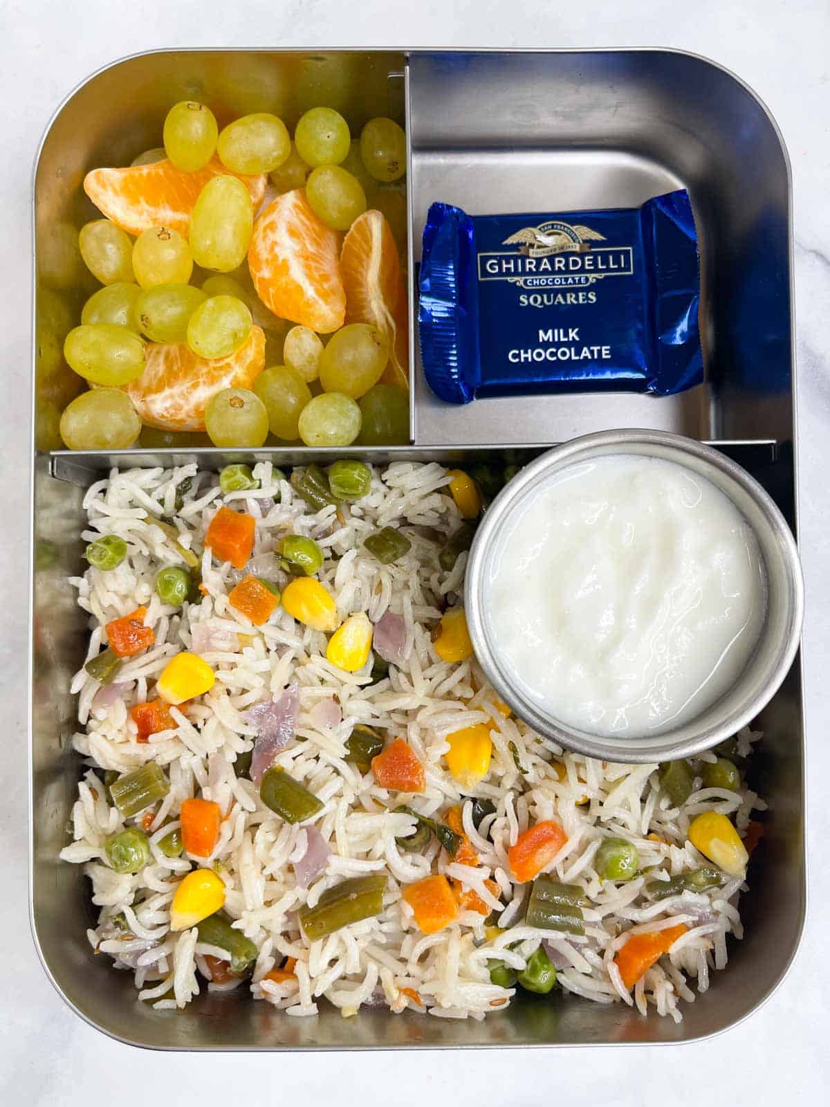 vegetable pulao with yogurt, fruits and chocolate in bento school lunch box