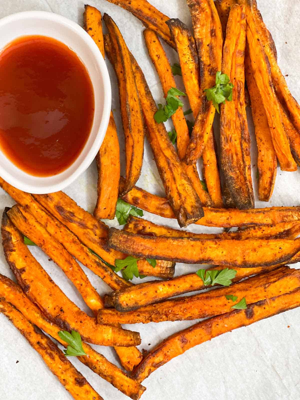 air fryer sweet potato fries served on a plate garnished with cilantro with ketchup on the side