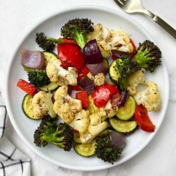 roasted vegetable medly in a white plate with fork on the side