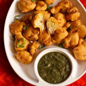 gobi pakora served on a plate with coriander mint chutney on the side.