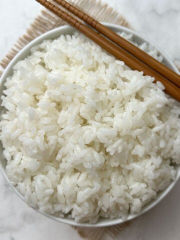 instant pot calrose rice served in a white bow with chopsticks on the top