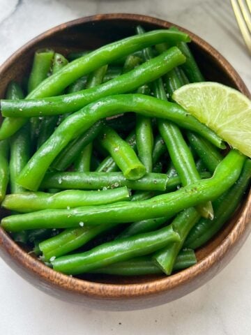 cooked green beans vegetable served in a bowl with lime in top