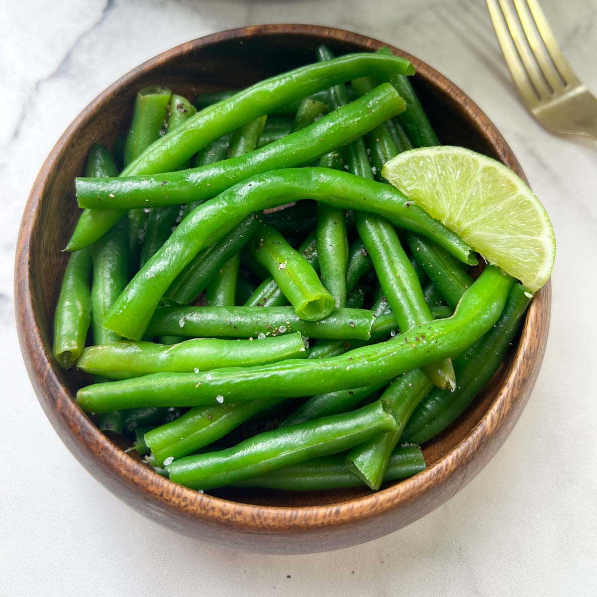 cooked green beans vegetable served in a bowl with lime in top