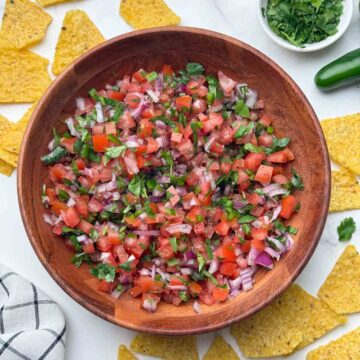 pico de gallo served in a wooden bowl with side of tortilla chips and coriander.