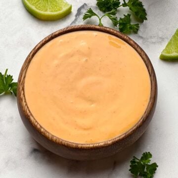 sriracha mayonnaise dip served in a bowl with lime wedges on the side