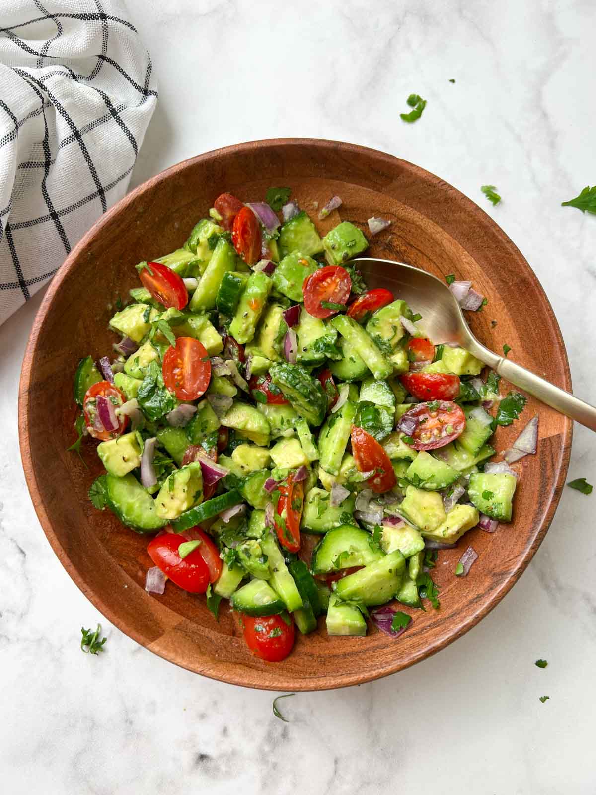 avocado cucumber salad served in a bowl with a spoon