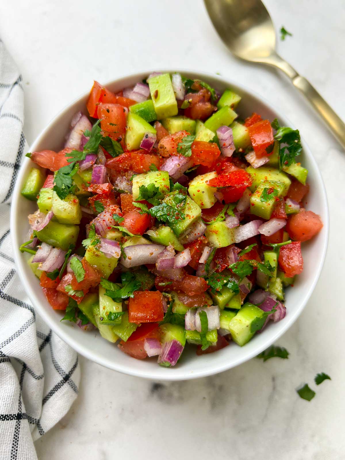 kachumber salad served in a bowl with spoon on the side