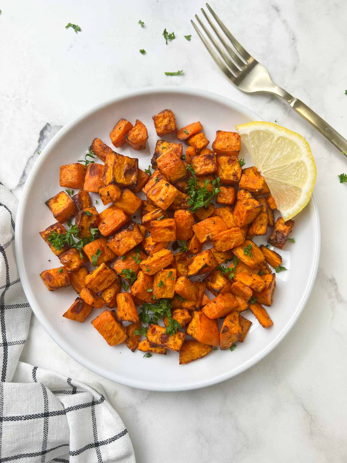 air fryer sweet potatoes recipe served on a plate with lemon wedge on the top