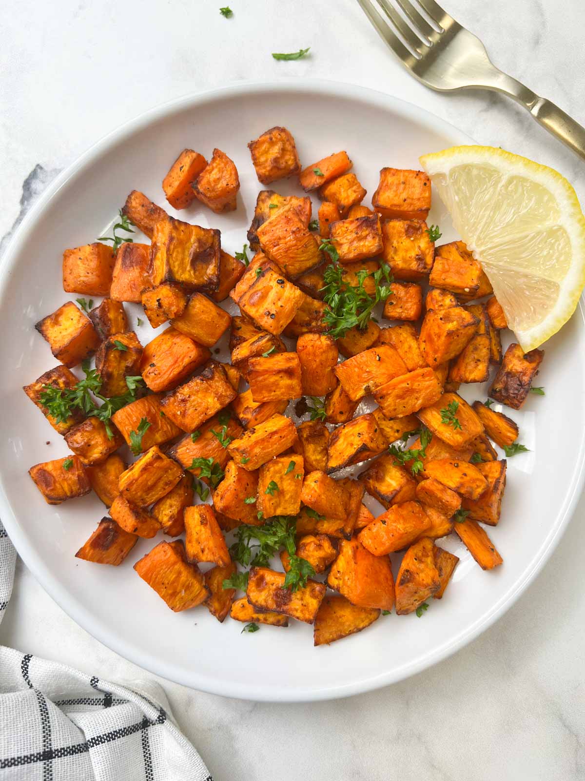 roasted sweet potatoes recipe served on a plate with lemon wedge on the top