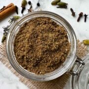 homemade chai masala powder (tea masala) in a mason spice jar with whole on the side