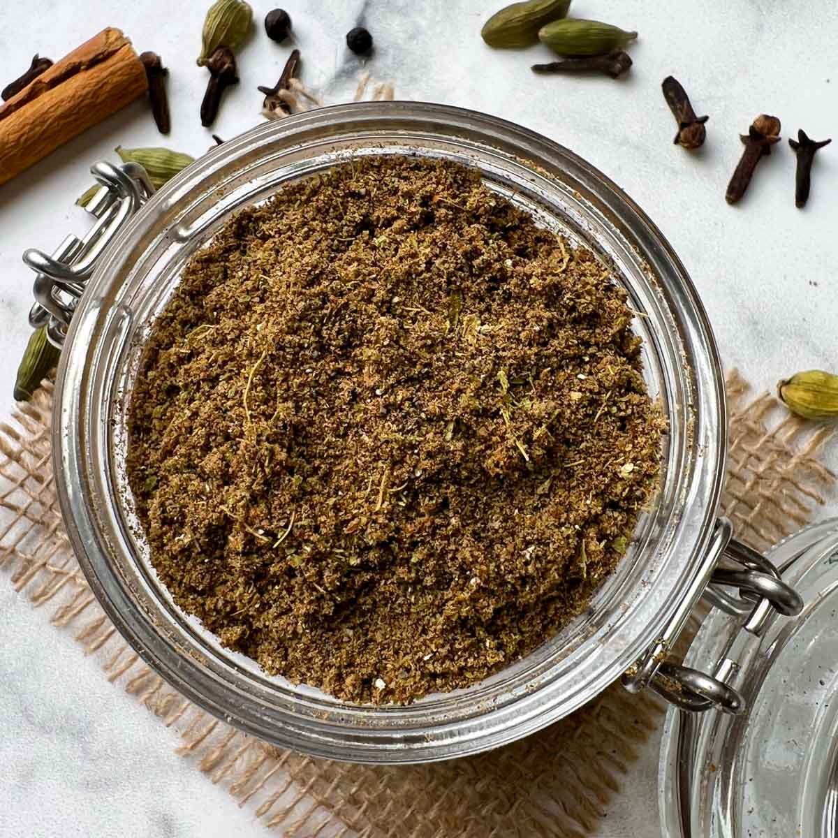 homemade chai masala powder (tea masala) in a mason spice jar with whole on the side