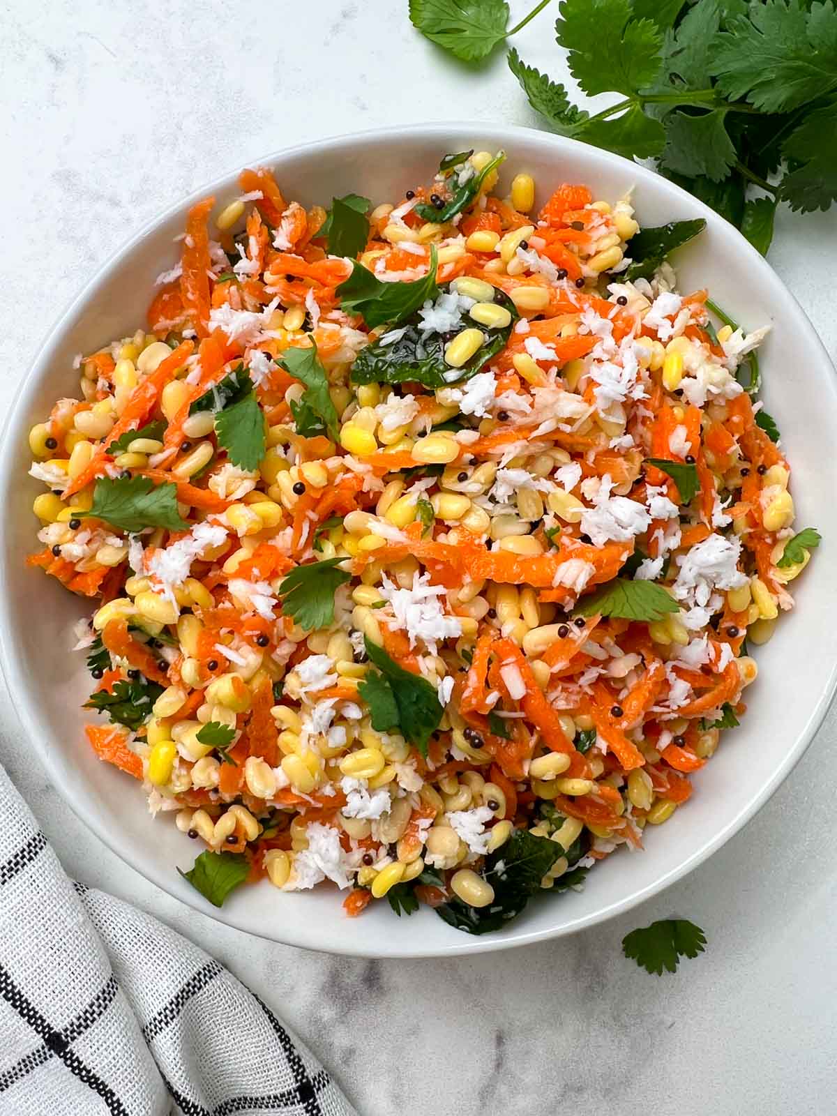 moong dal carrot salad served in a bowl garnished with coconut and coriander leaves