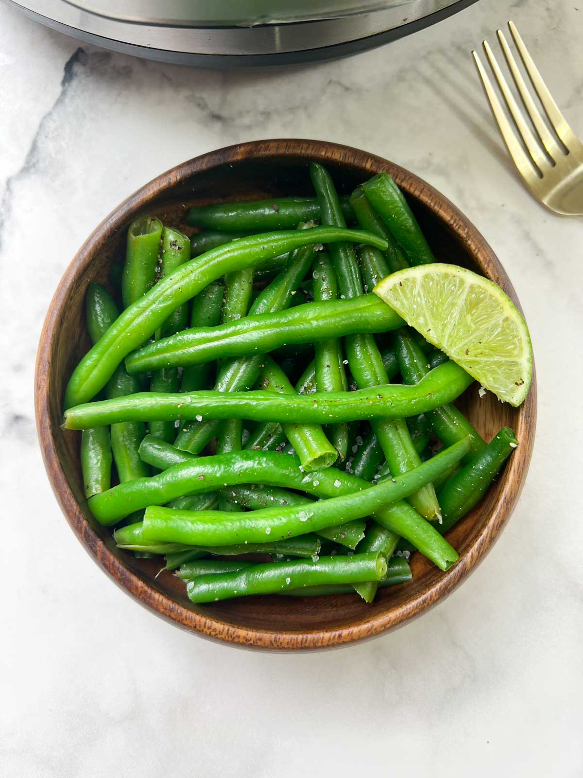 cooked green beans vegetable served in a bowl with lime in top