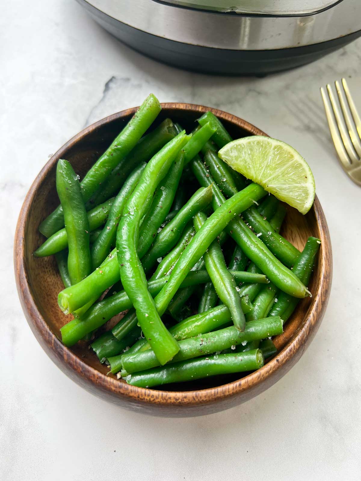 steamed green beans served in a bowl with lime wedge on top 