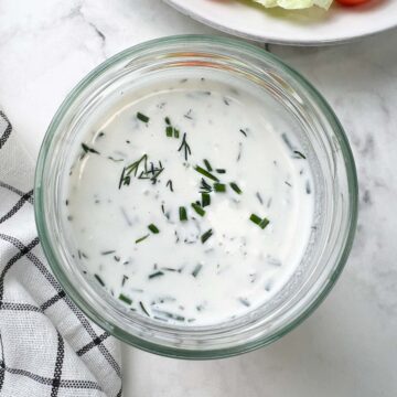 homemade ranch dressing/dip in a glass jar garnished with fresh herbs