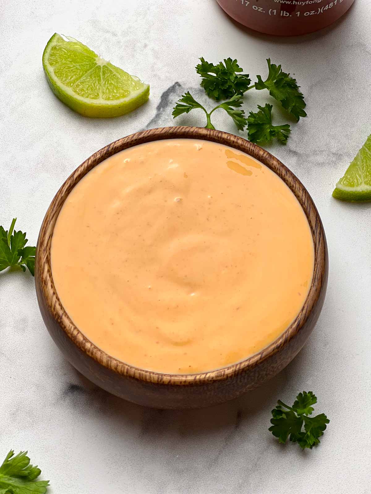 sriracha mayonnaise dip served in a bowl with lime wedges on the side