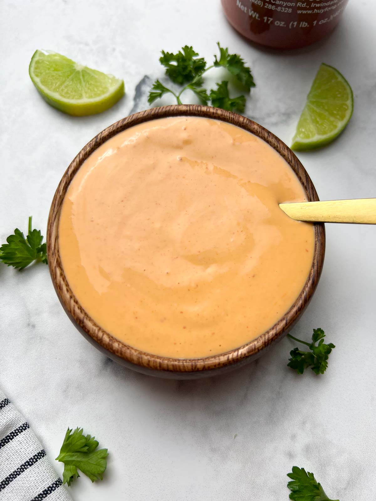 spicy mayo sauce served in a bowl with a spoon with lime wedges on the side