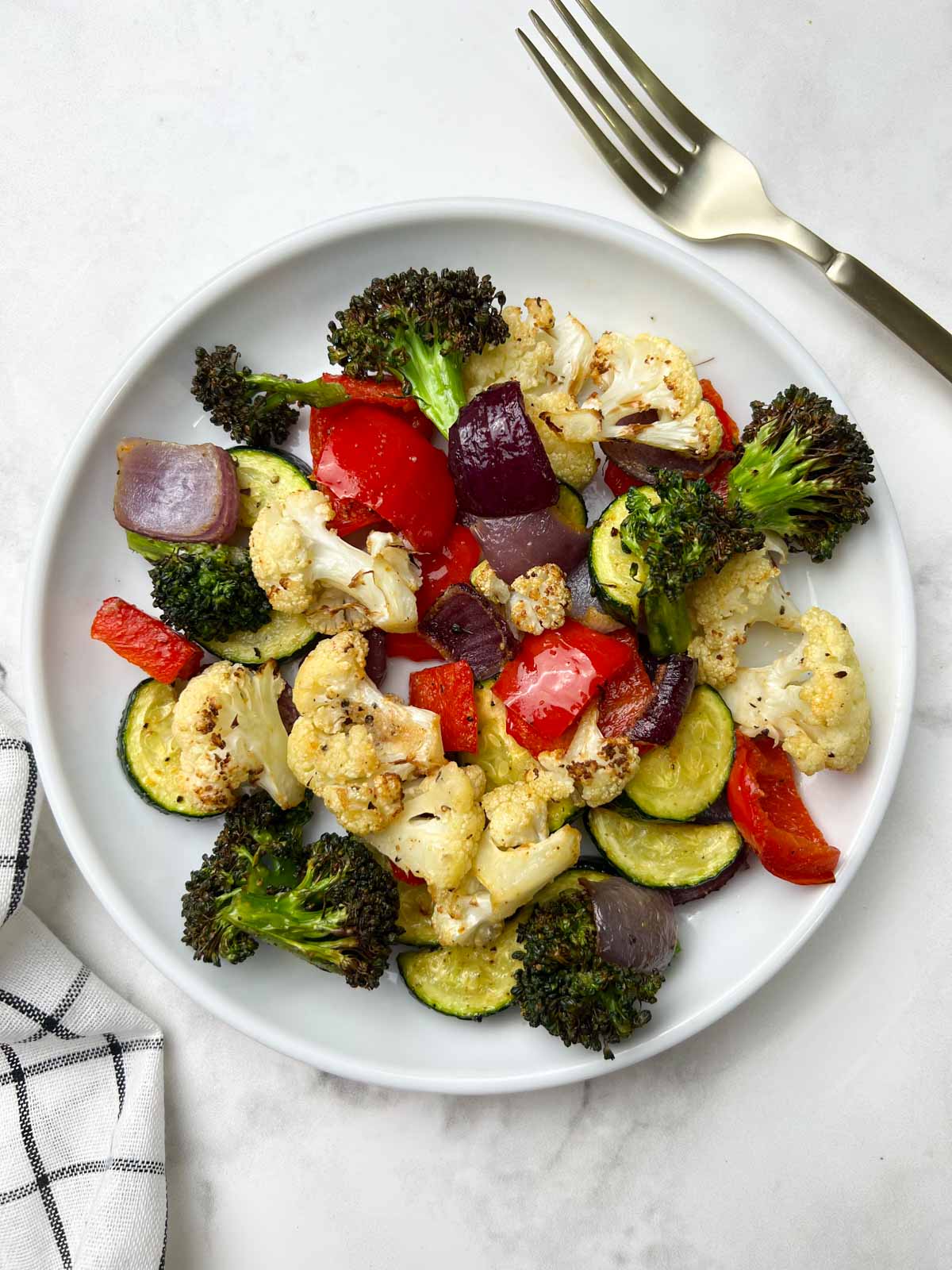 roasted vegetable medly in a white plate with fork on the side