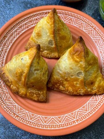air fryer samosas on a plate with chutneys on the side