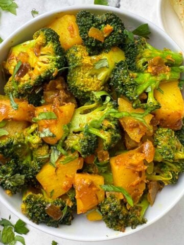 indian broccoli potato stir fry served in a bowl with lime edge on the side