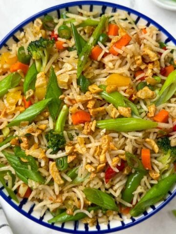 burnt garlic vegetable fried rice served in a bowl garnished with spring onions and burnt garlic