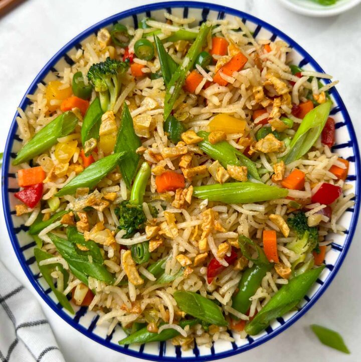 burnt garlic vegetable fried rice served in a bowl garnished with spring onions and burnt garlic