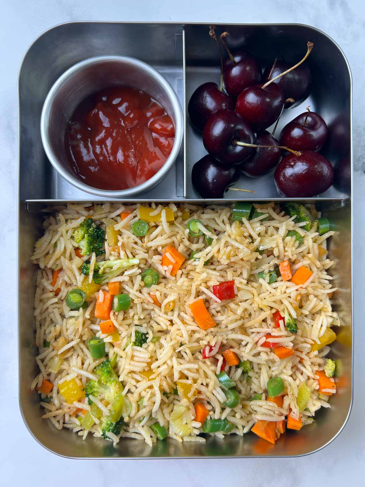 burnt garlic fried rice with ketchup and red cherries in bento steel lunch box