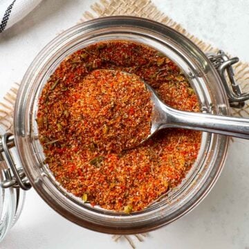 homemade cajun seasoning mix in a glass jar with a spoon full of spice blend