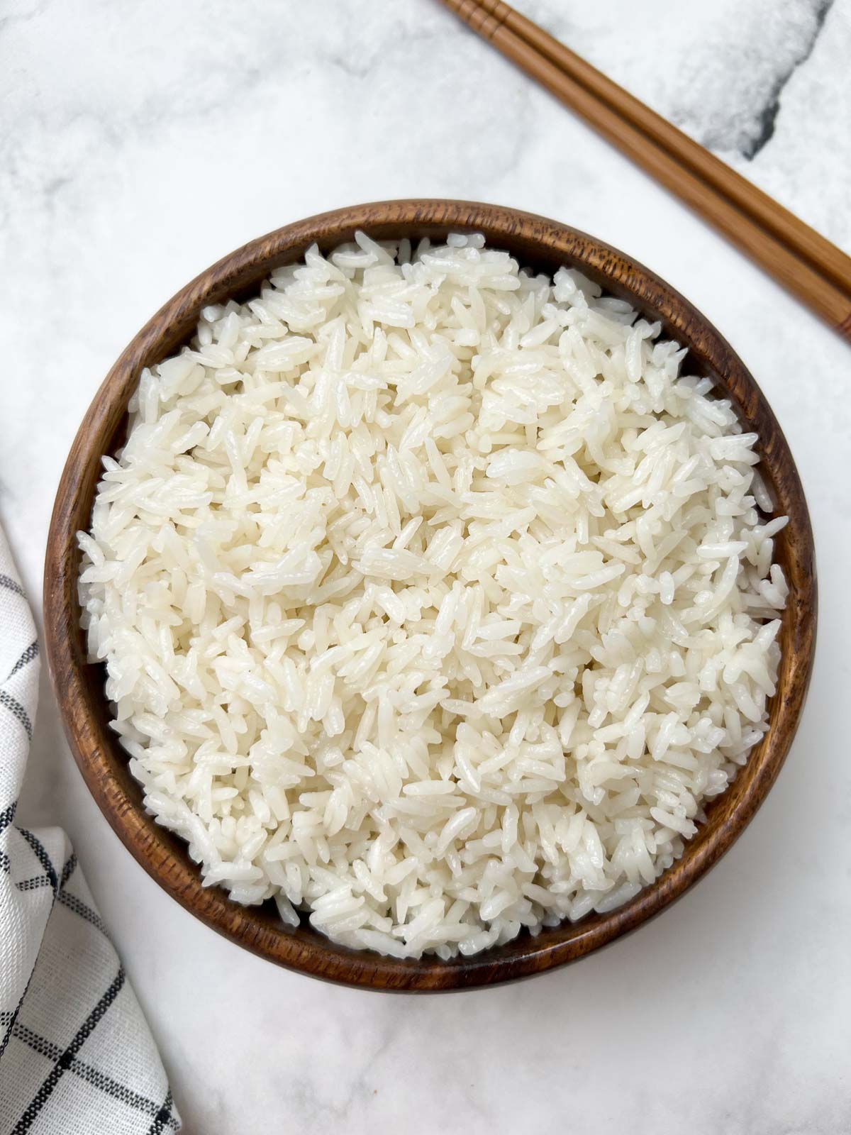 instant pot coconut rice served in a wooden bowl with chopsticks on the side