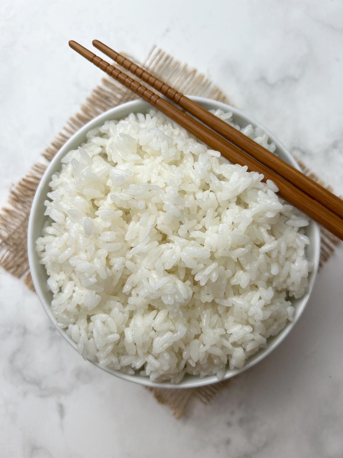 instant pot calrose rice served in a white bow with chopsticks on the top