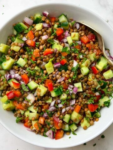 brown lentil salad served in a white bowl with a spoon