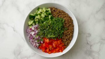 step to add all salad ingredients to a bowl