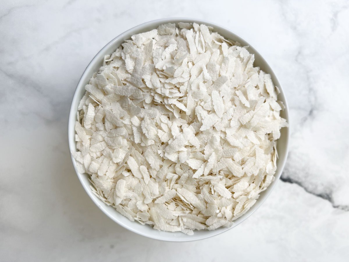 Thick flattened rice (poha) in a white bowl