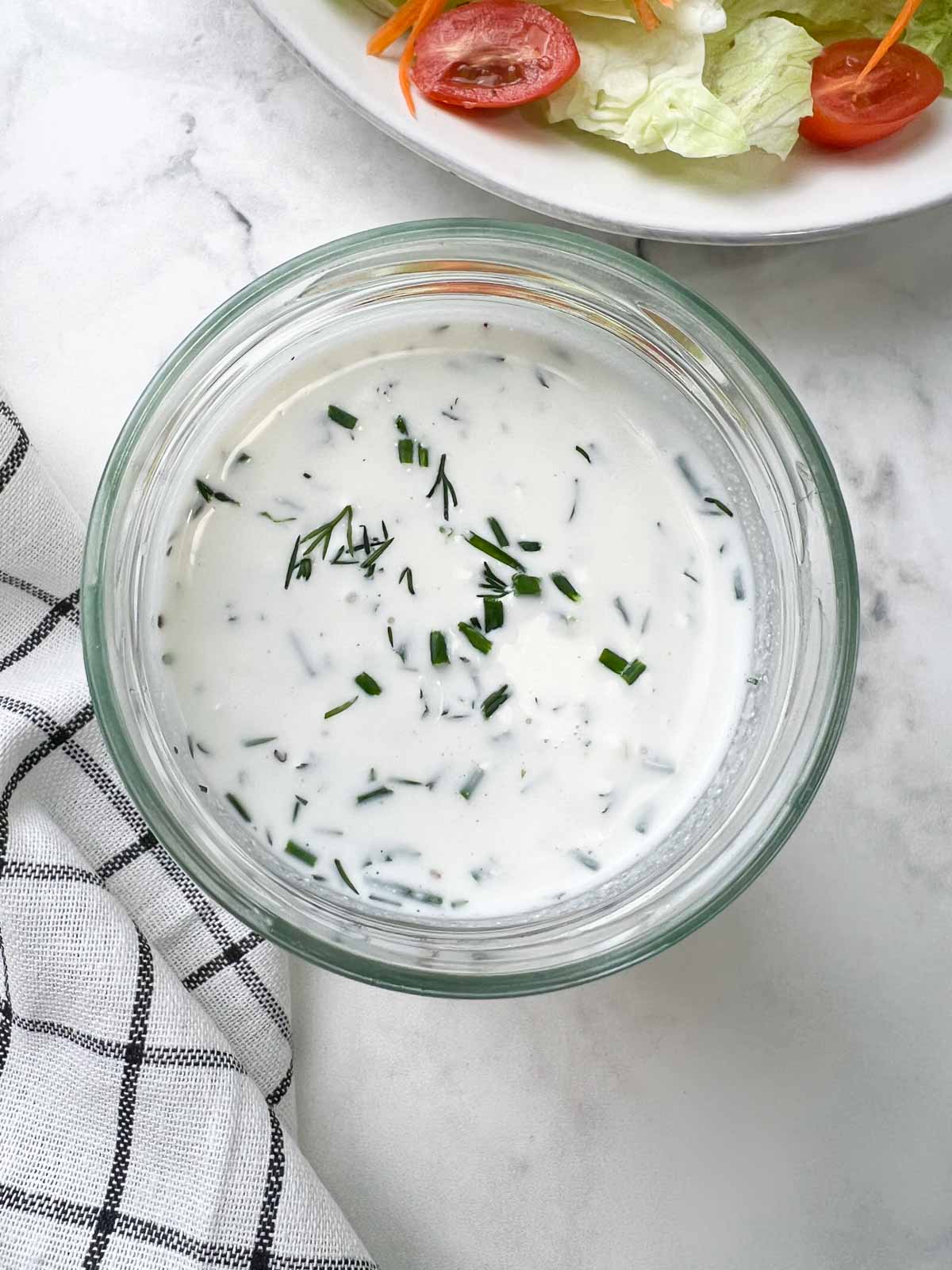 homemade ranch dressing/dip in a glass jar garnished with fresh herbs