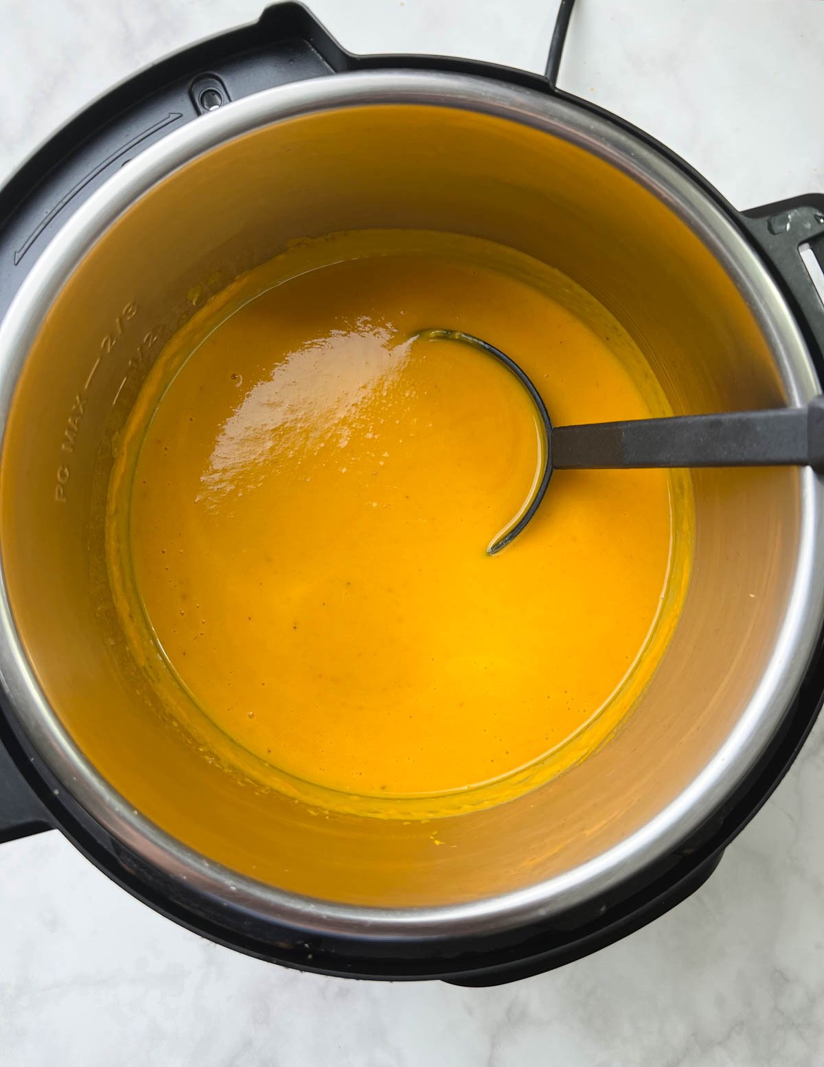 sweet potato carrot soup in instant pot insert with a laddle