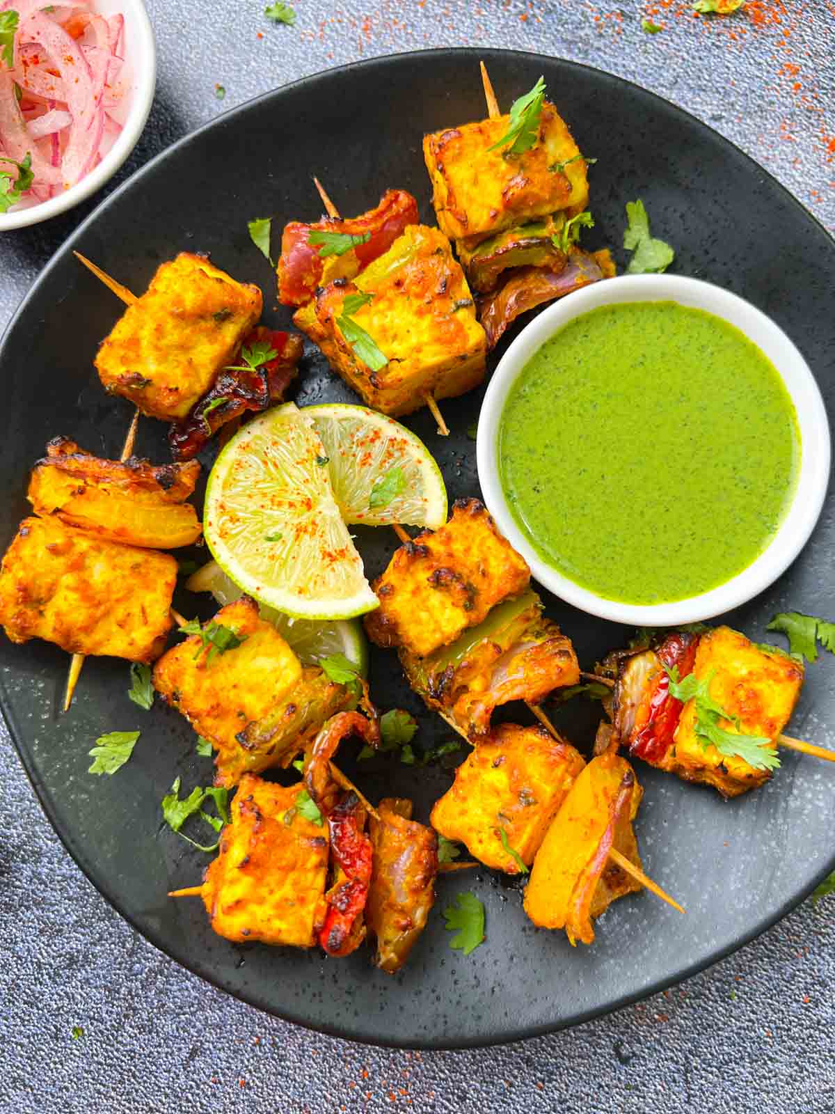 air fryer tandoori tofu tikka served in a plate with green chutney and onions on the side