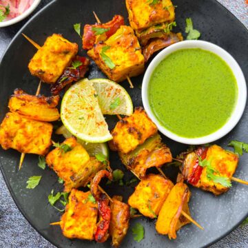 air fryer tandoori tofu tikka served in a plate with green chutney and onions on the side