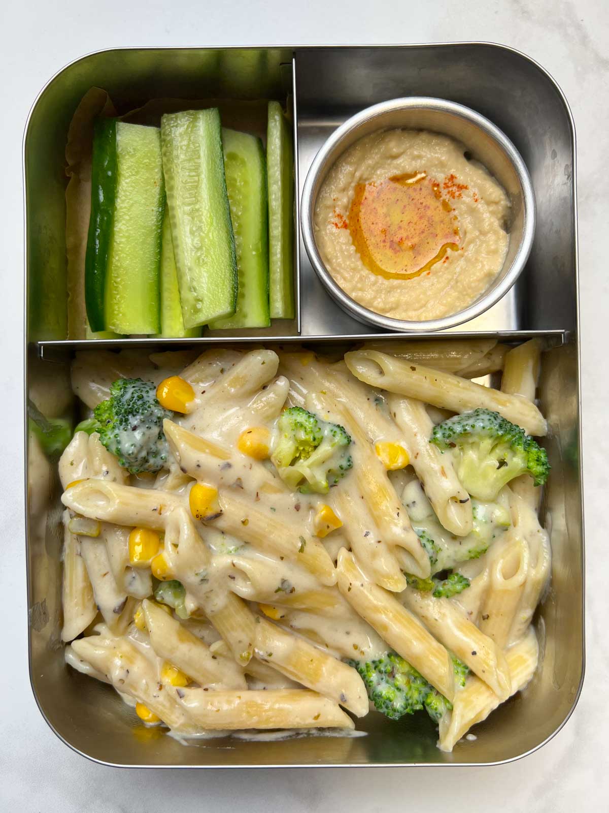 white sauce penne pasta with hummus and cucumber in bento steel box