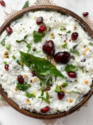 curd rice (thayir saddam) served in a wooden bowl with the tempering on the top