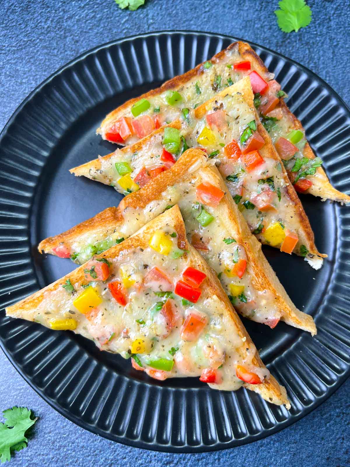 Veg chili cheese toast placed in a layer on a black plate