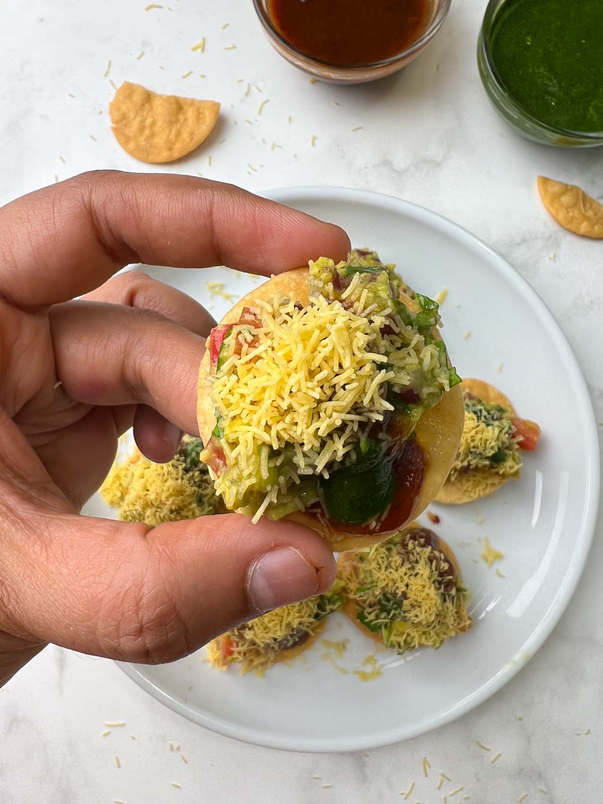 crispy poori in a hand with chutneys on the side