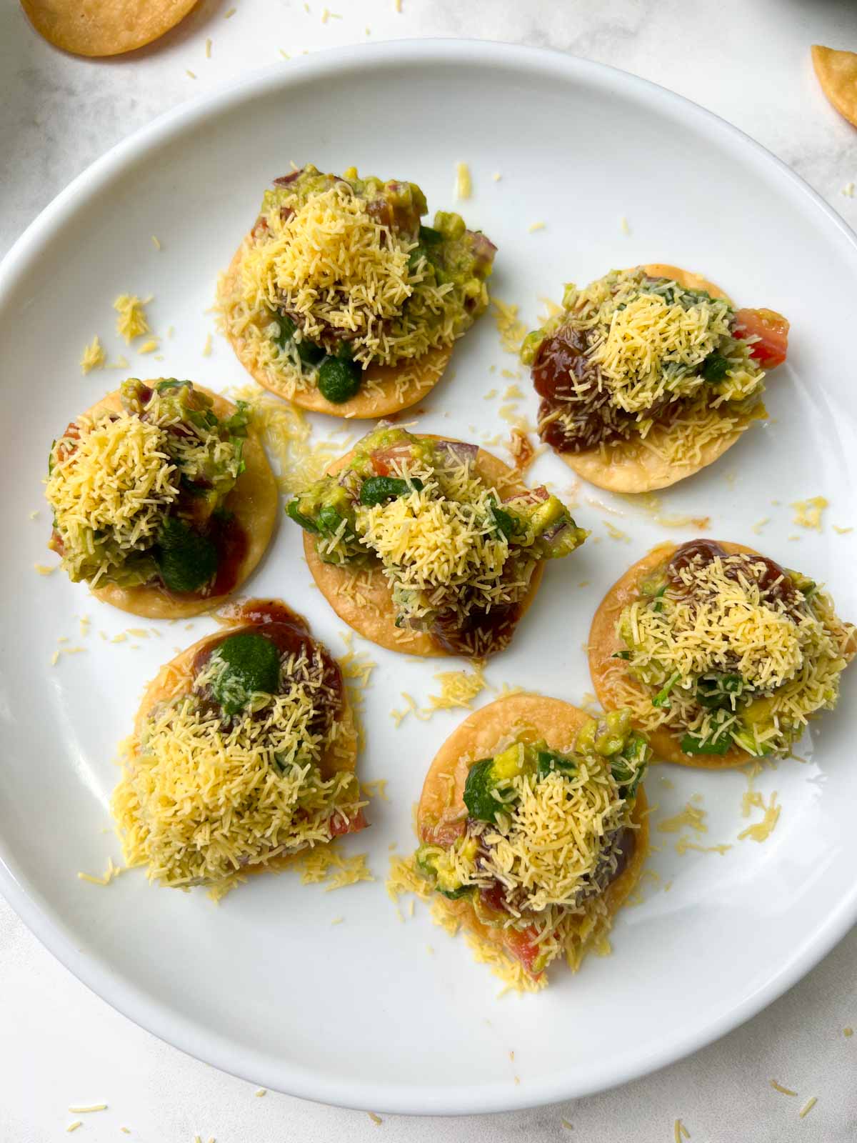 gucamole papdi chaat served on a plate topped with sev