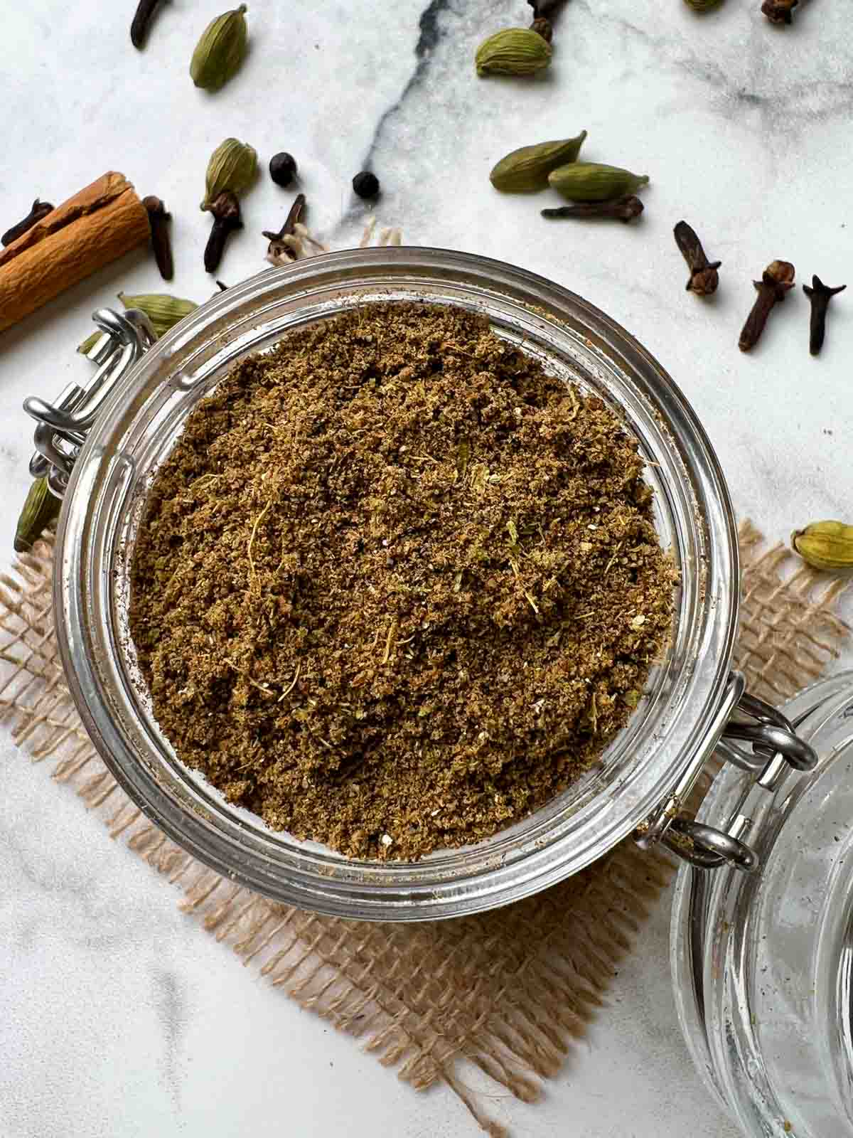 homemade chai masala powder (tea masala) in a mason spice jar with whole on the side