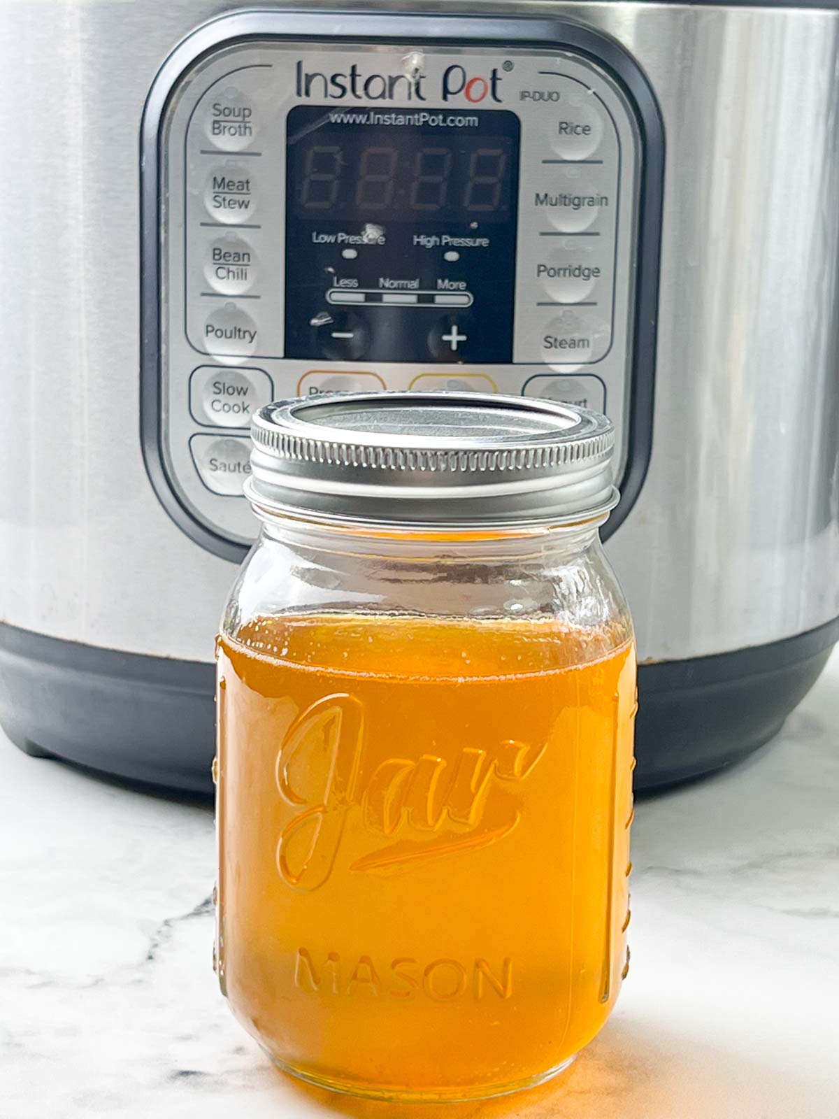 homemade ghee stored in a glass jar in front of instant pot