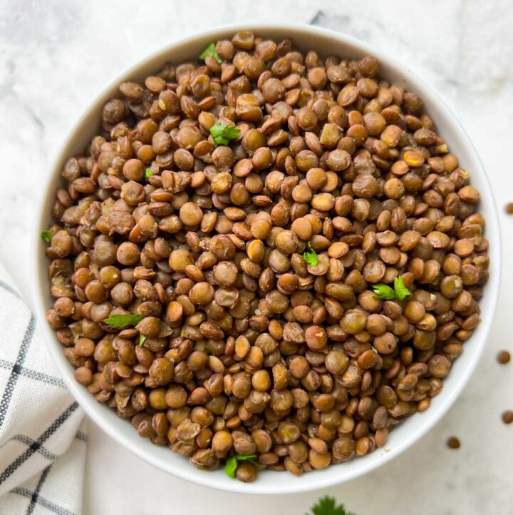 instant pot perfectly cooked lentils in a white bowl garnished with coriander leaves