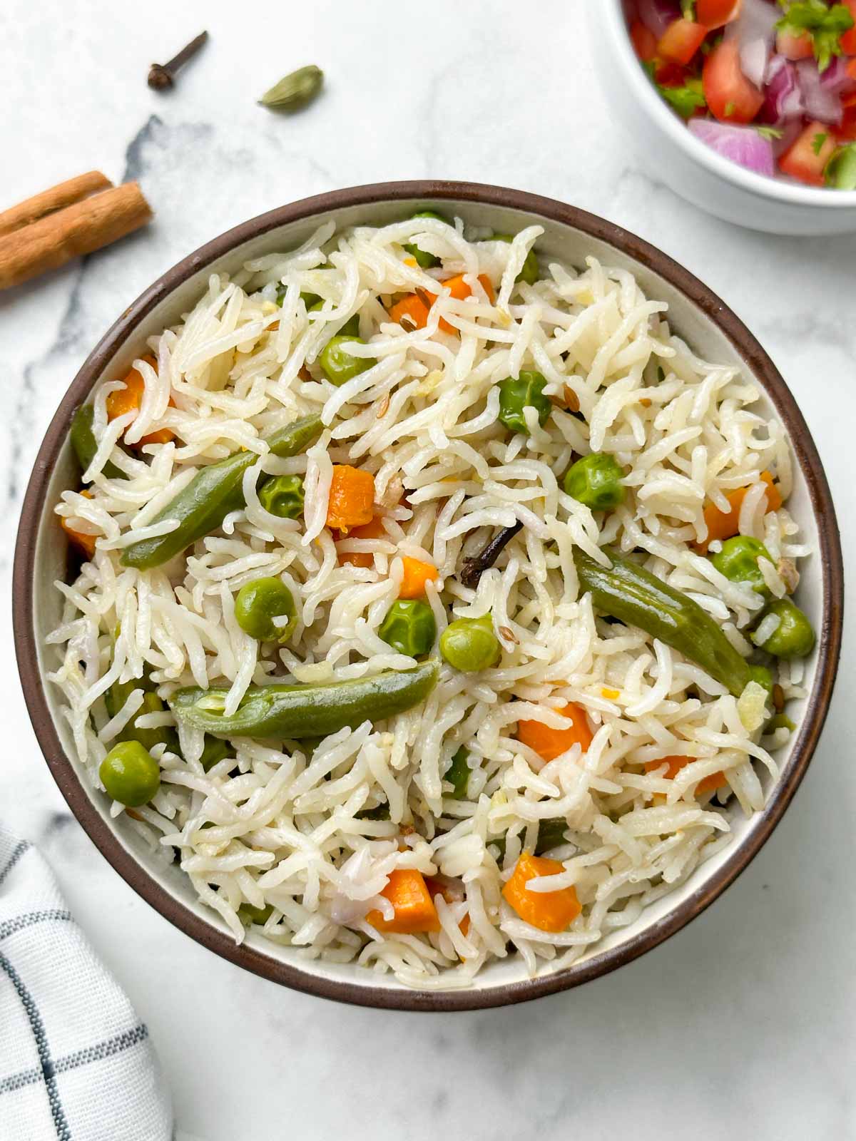 instant pot coconut milk pulao served in a bowl with spices and salad on the side