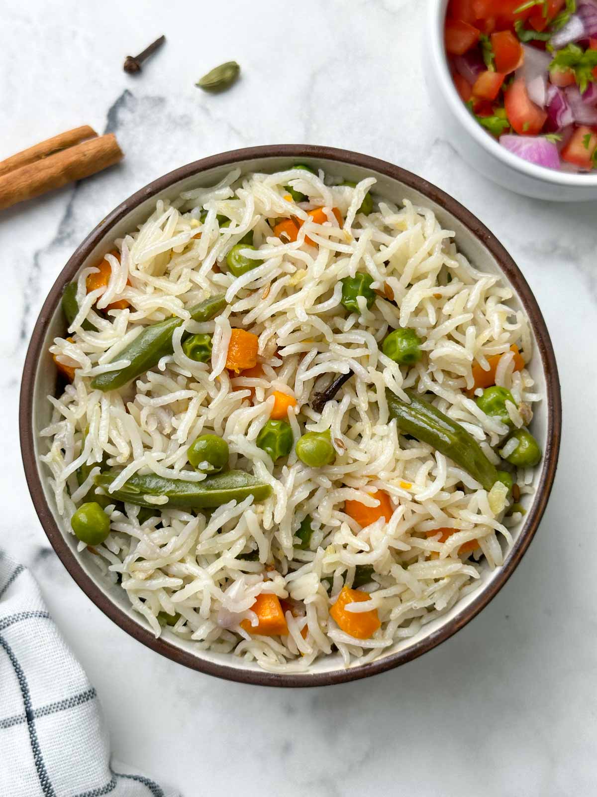 instant pot coconut milk pulao served in a bowl with spices and salad on the side