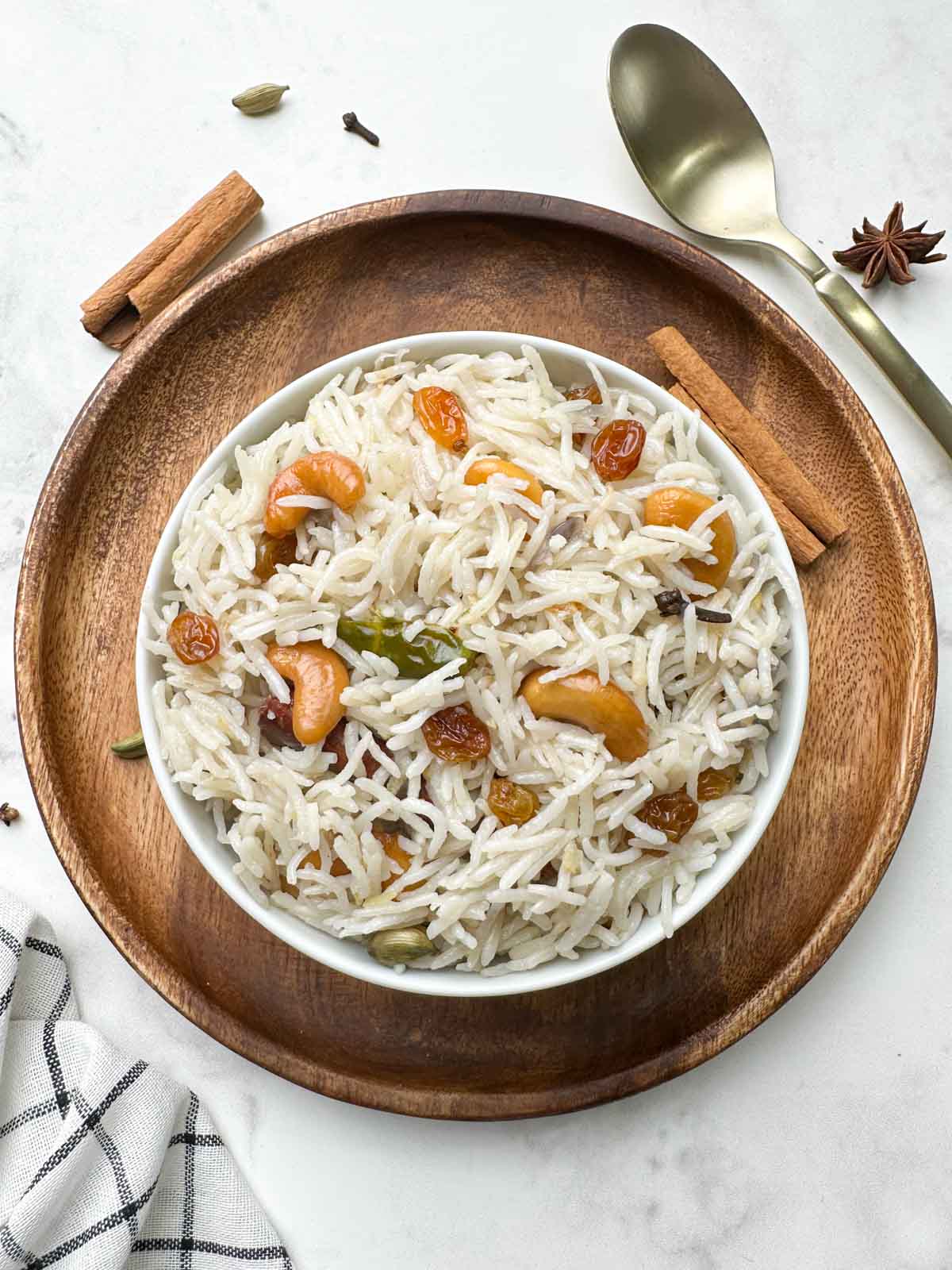 instant pot ghee rice served in a white bowl garnished with nuts and spices on the side