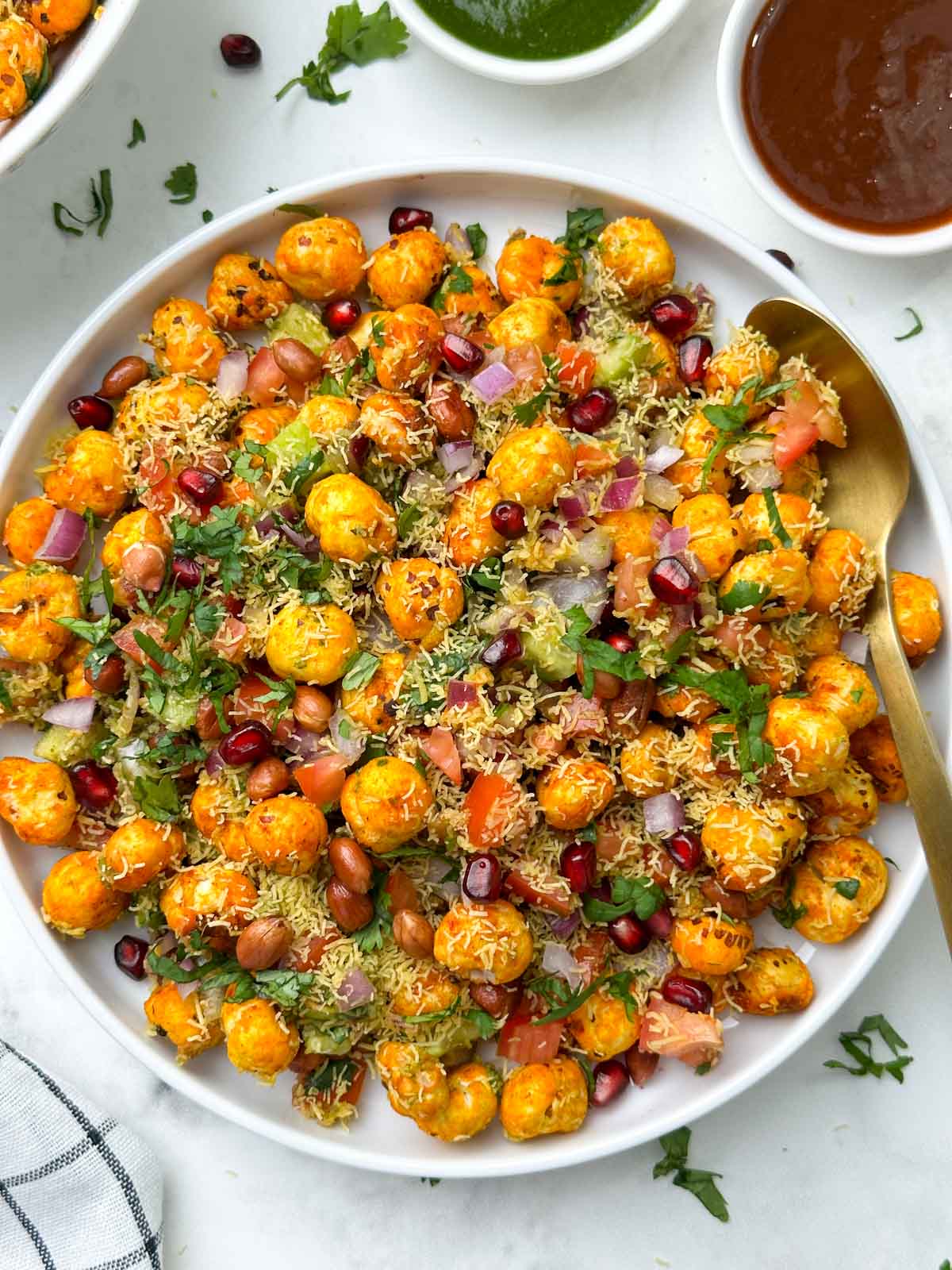 phool makhana bhel served in a plate garnished with sev and pomegranate with chutneys on the side