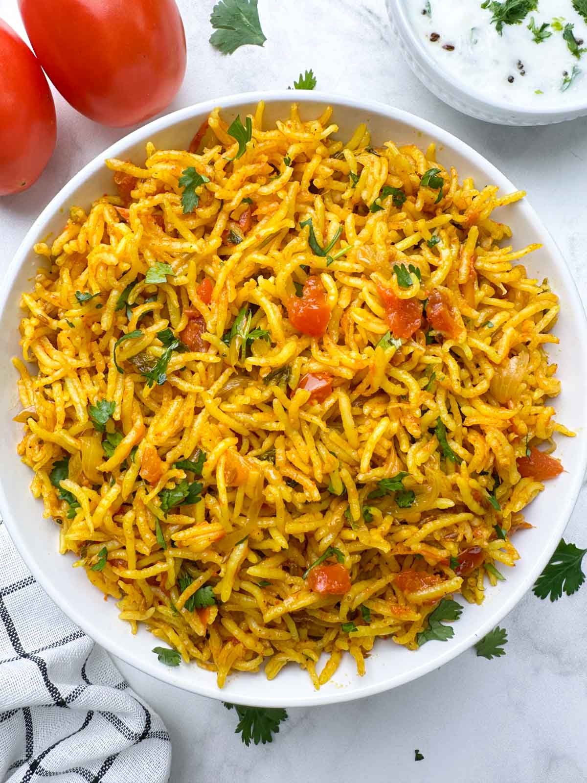 instant pot tomato rice served in a white bowl with whole tomatoes on the side